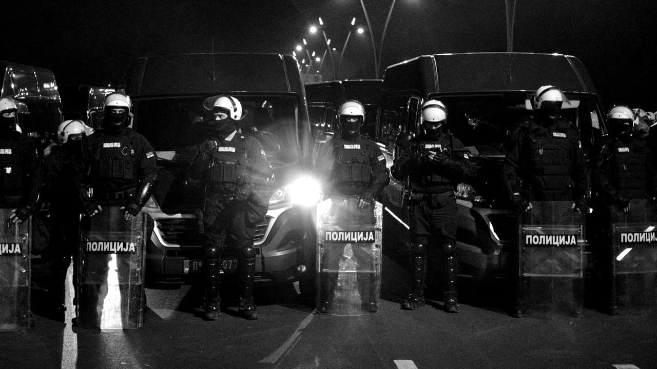 Still from the rear camera clip: a line of riot police on a road at night